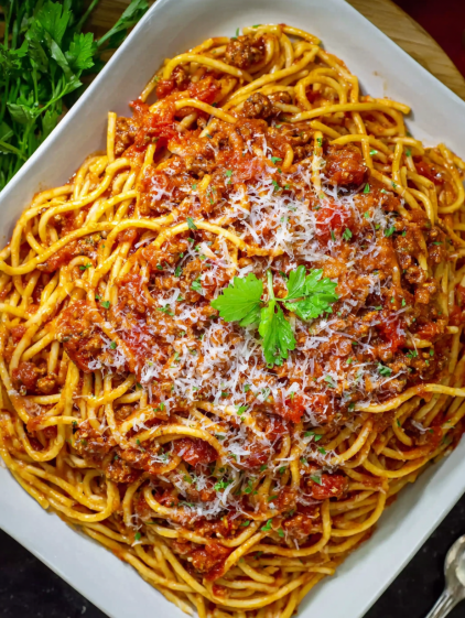 A bowl of spaghetti with meat sauce and cheese.
