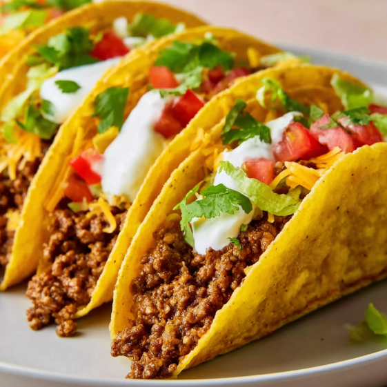 A plate of tacos with white cheese and tomatoes.