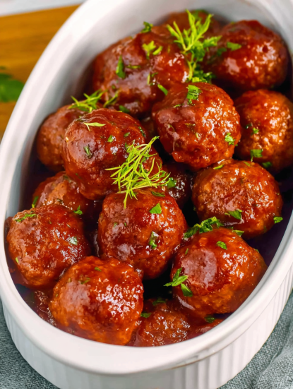 A bowl of meatballs with a green garnish.
