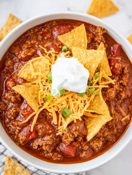 A bowl of chili with a dollop of sour cream on top.