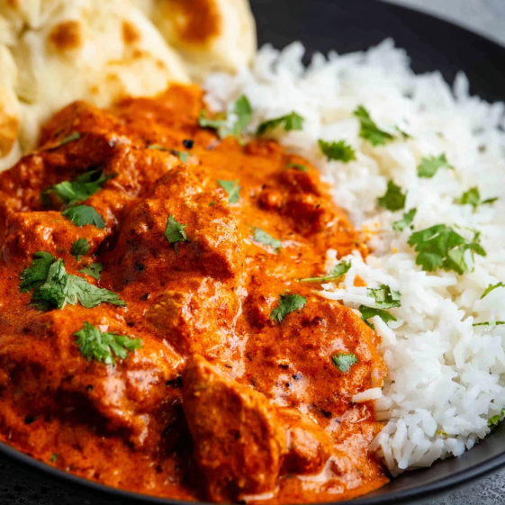 A bowl of chicken tikka masala with rice.