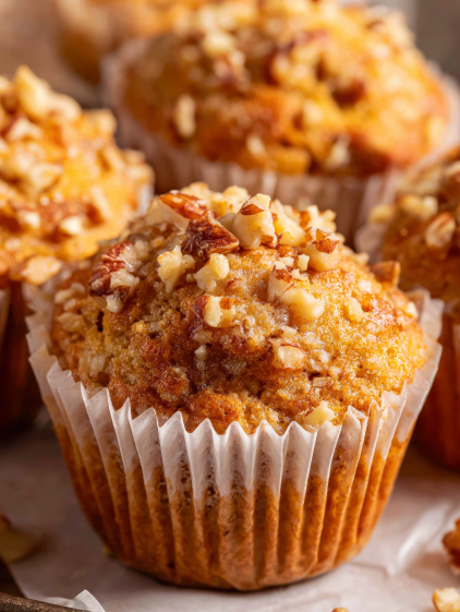 A close up of a muffin with nuts on top.