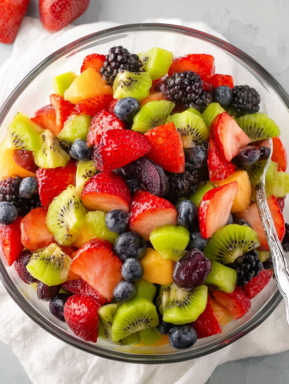 A bowl of fruit with strawberries, kiwi, blueberries, and blackberries.