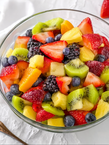 A bowl of fruit with strawberries, kiwi, blueberries, and blackberries.