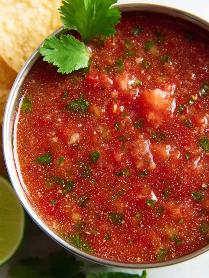 A bowl of salsa with a green garnish.