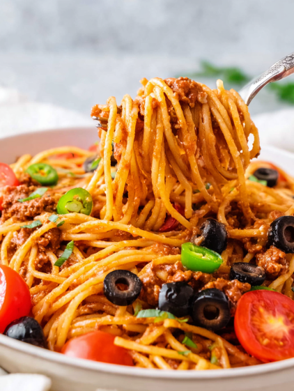 A spoonful of spaghetti with meat sauce and vegetables.