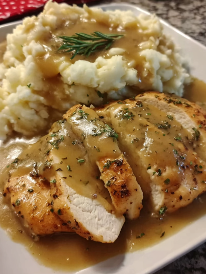 A plate of chicken with gravy and mashed potatoes.