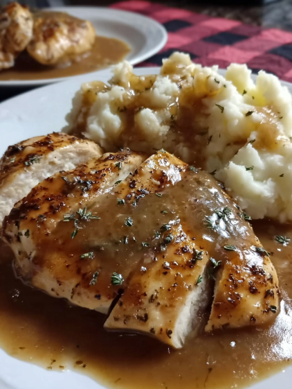 A plate of chicken and potatoes with gravy.