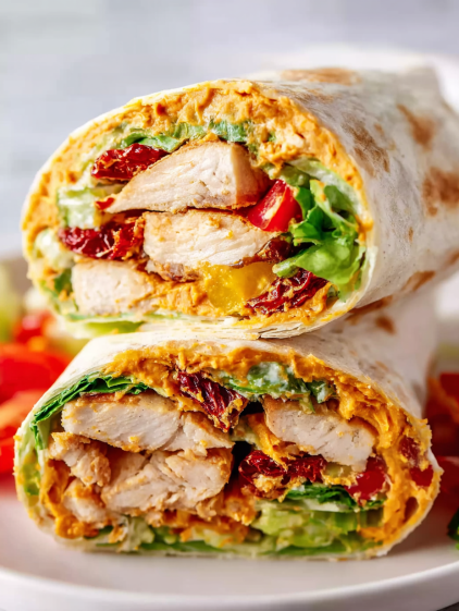 A sandwich with chicken, lettuce, tomato, and cheese.