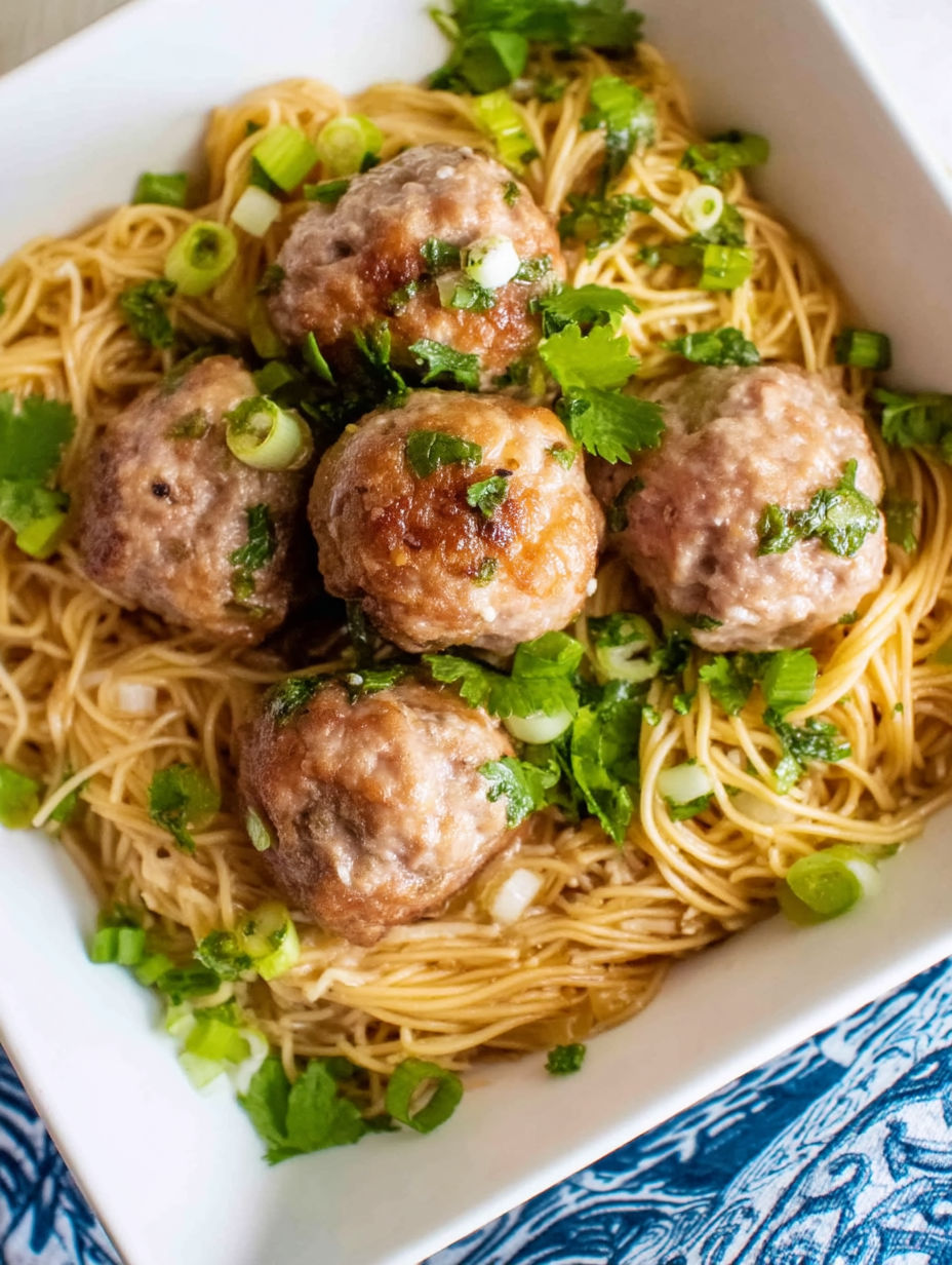 A bowl of Asian meatballs with noodles.