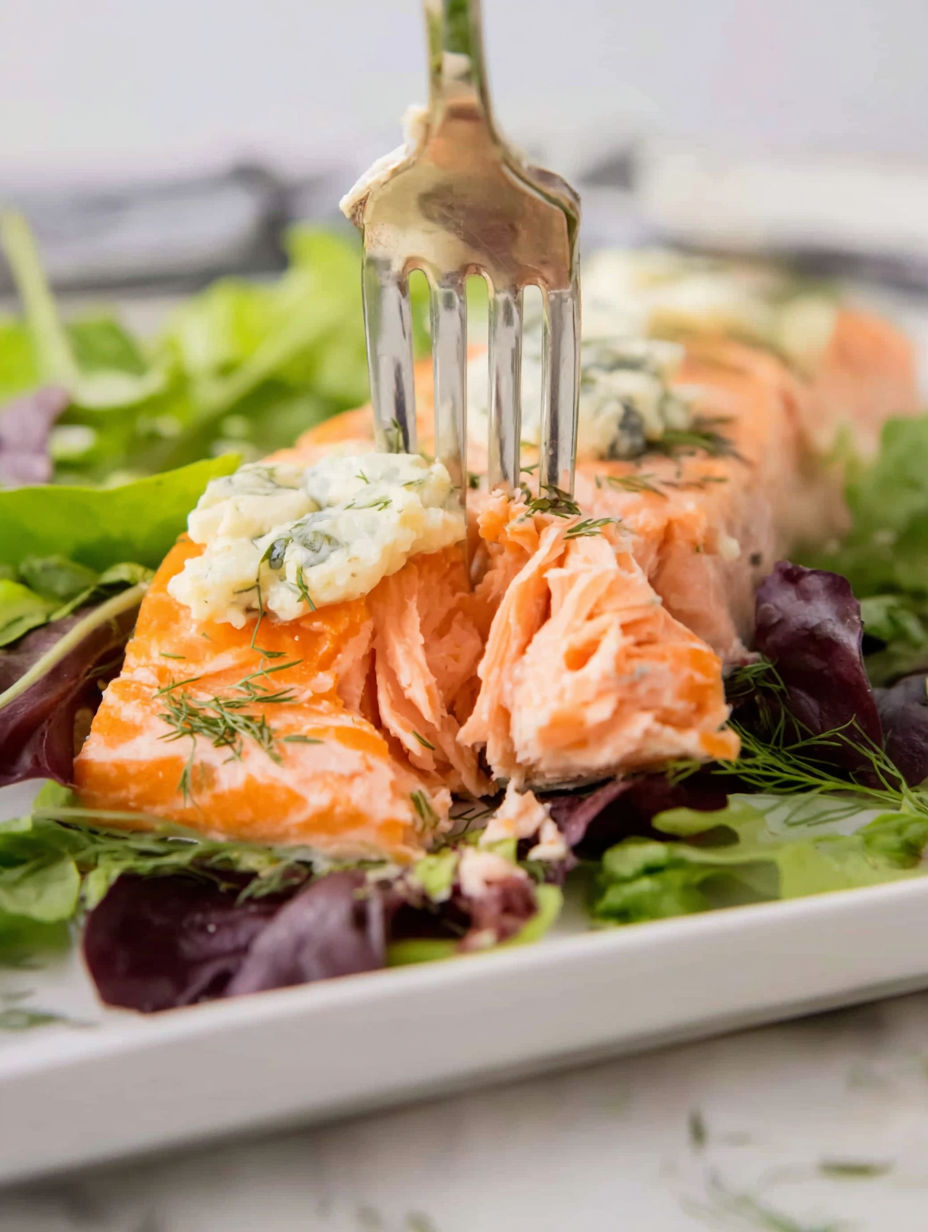 A fork is stuck in a piece of salmon.