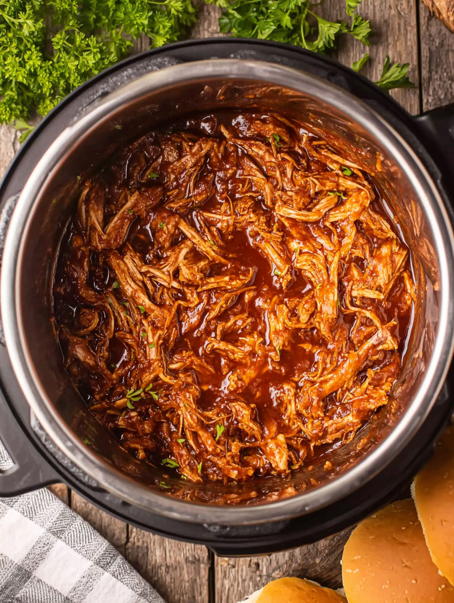 A pot of BBQ chicken with a green herb on top.