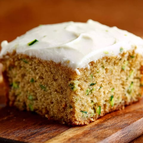 A slice of cake with white frosting and green toppings.