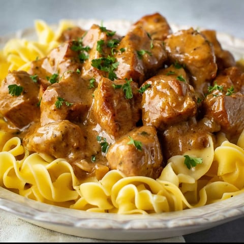 A plate of pork bites with gravy.