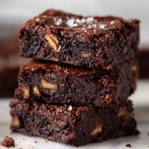 A stack of brownies with nuts on top.