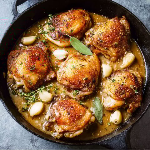 A pan of garlic chicken with green herbs.