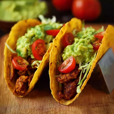 Two tacos with meat and tomatoes.