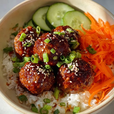 A bowl of meatballs with rice and vegetables.