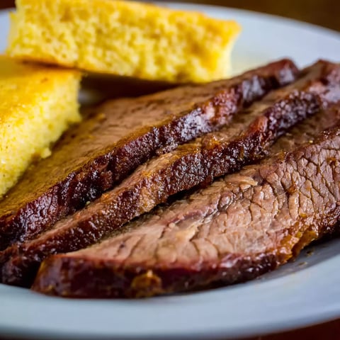 A plate of beef brisket with a biscuit on the side.