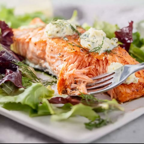 A salmon dish with a fork and a side of lettuce.