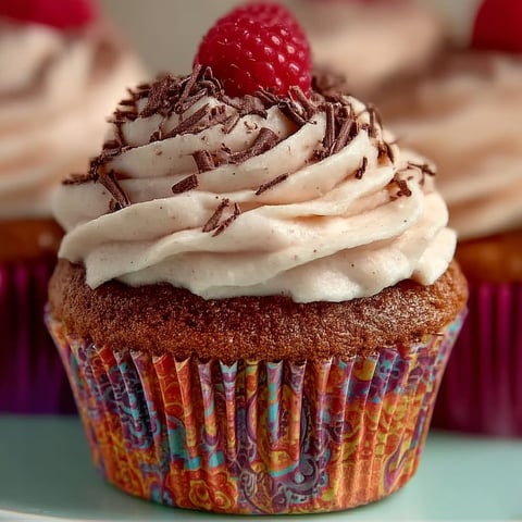 A cupcake with chocolate and raspberry toppings.